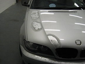 A silver BMW being prepared for paint after repairs