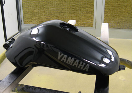 A black Yamaha fuel tank, freshly painted